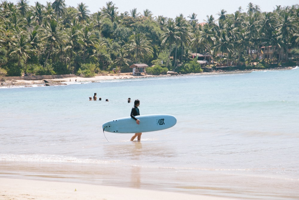 man in black wet suit holding white surfboard on beach during daytime