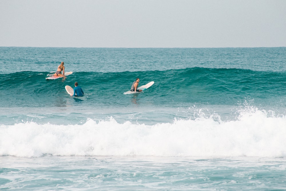 2 men surfing on sea waves during daytime