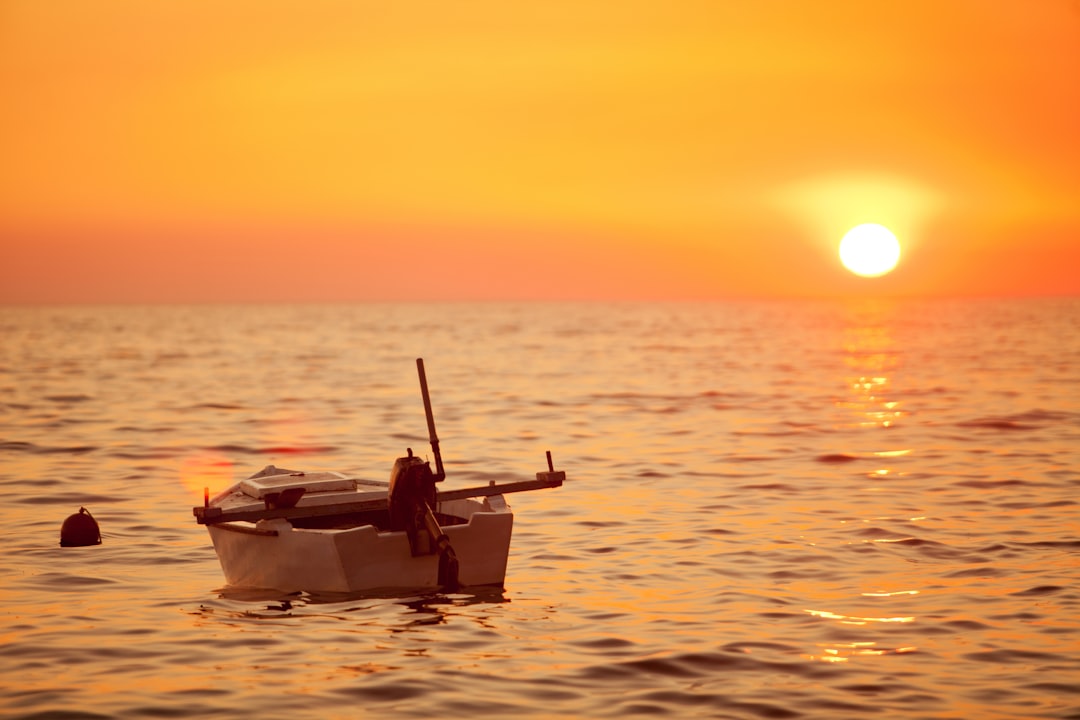 white boat on sea during sunset