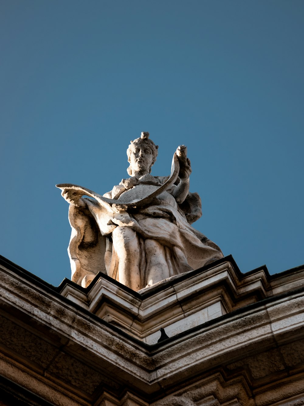 Una statua di una donna seduta sulla cima di un edificio