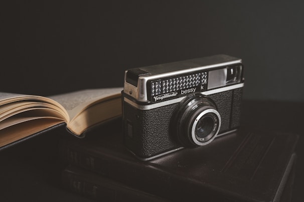 A close-up of a vintage camera resting on a stack of travel journals.