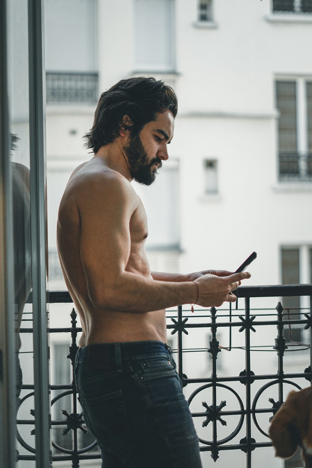 topless man in blue denim jeans holding smartphone