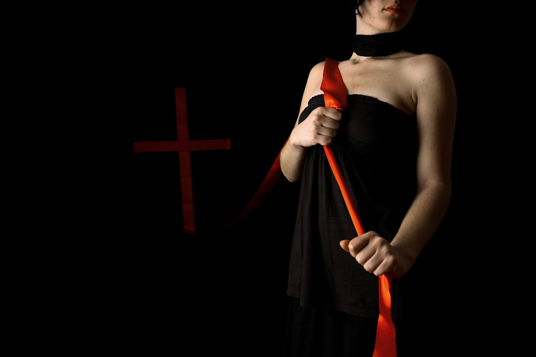 woman in black spaghetti strap dress holding red and black stick