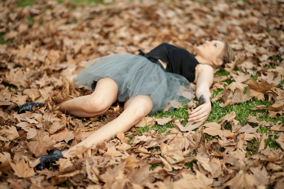 woman in gray dress lying on dried leaves