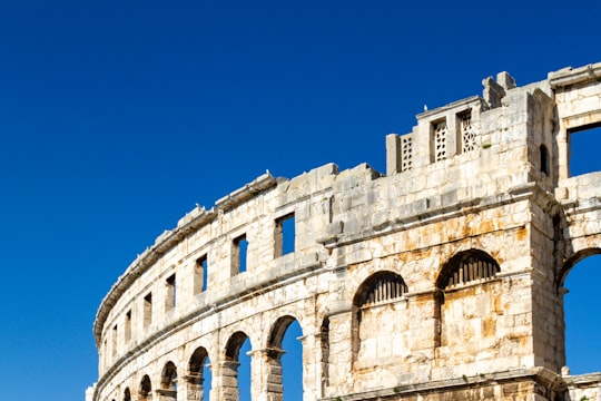 white concrete building under blue sky during daytime in Pula Arena Croatia