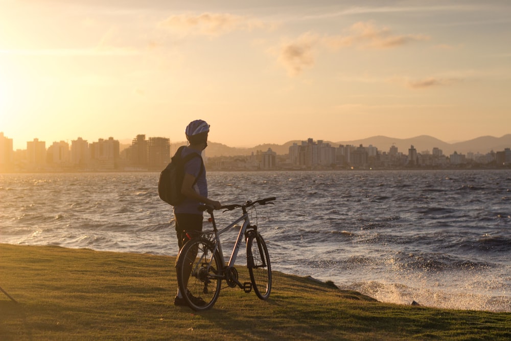 昼間、水域近くの緑の芝生原で自転車に乗る男性