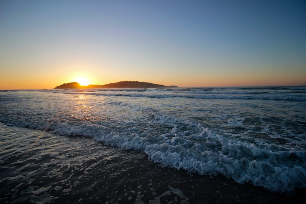 ocean waves crashing on shore during sunset