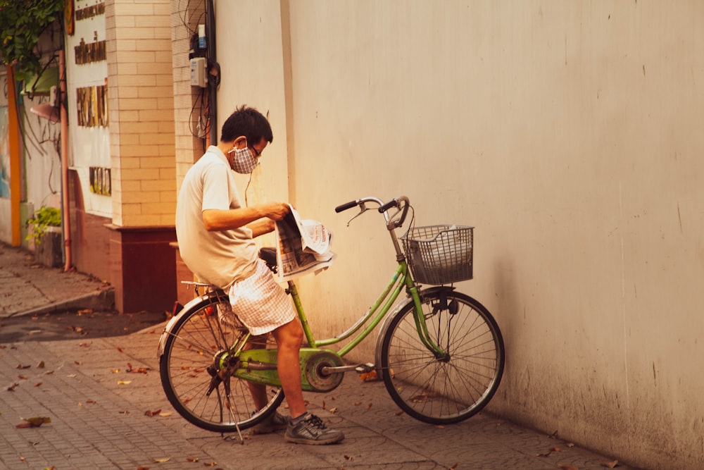 man in white t-shirt riding on green bicycle