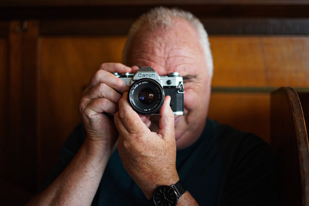 man in blue shirt holding gray and black camera