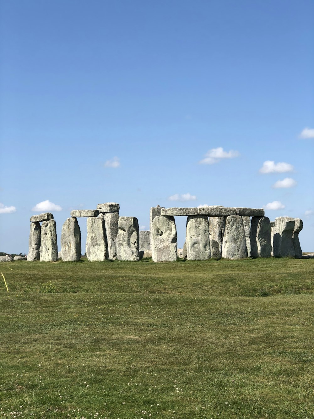 gray rock formation on green grass field under blue sky during daytime