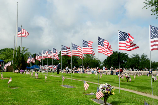 us a flags on green grass field under cloudy sky during daytime