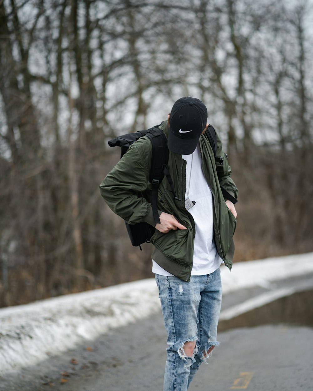 man in green jacket and blue denim jeans standing on snow covered ground during daytime