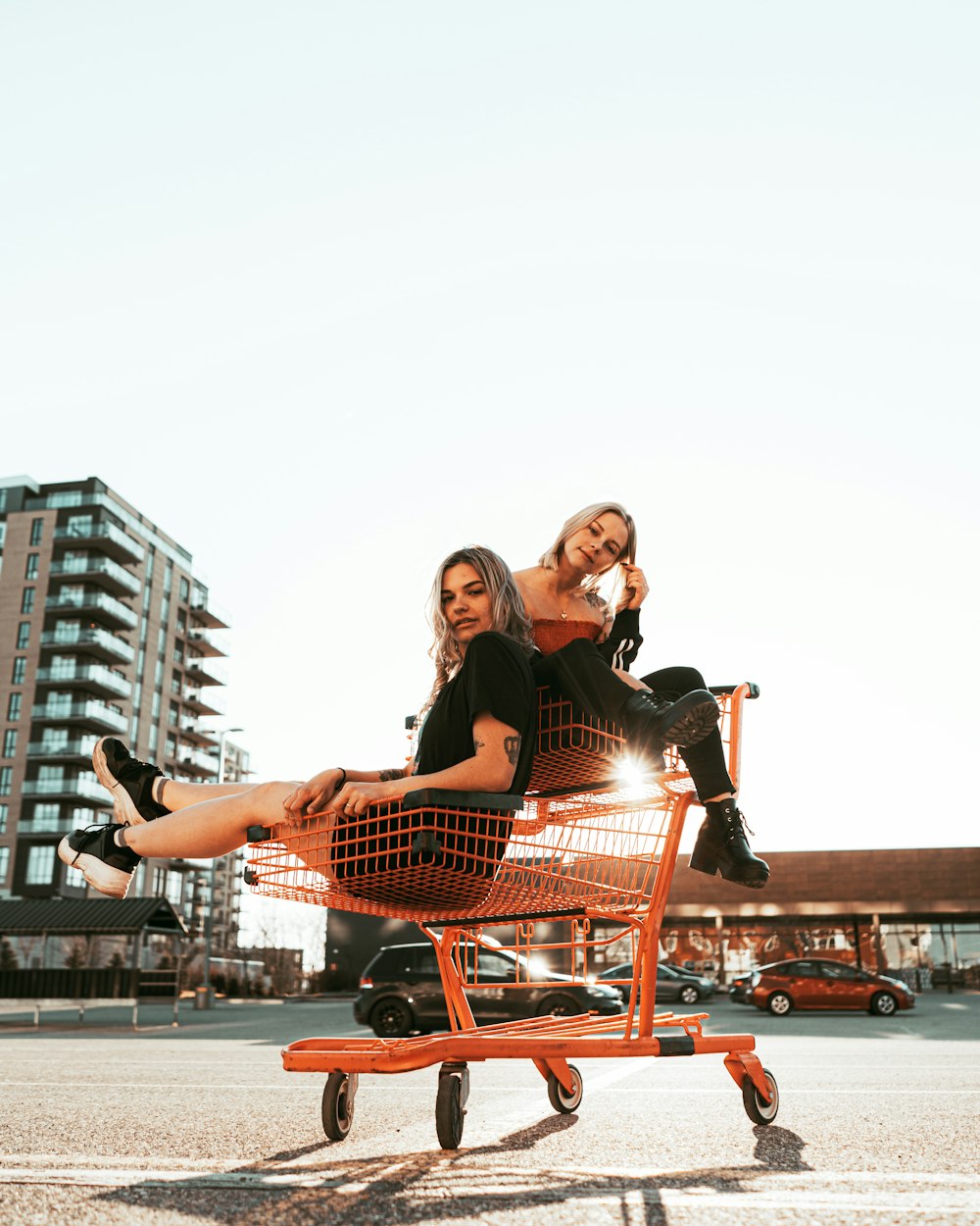 2 women sitting on red metal bench during daytime