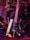 A black electric guitar with a beige strap is shown resting against a set of electronic drum pads. The guitar has a glossy black finish and silver tuning pegs. The background features various musical equipment including stands and wires, with purple and red lighting adding a warm and vibrant atmosphere.