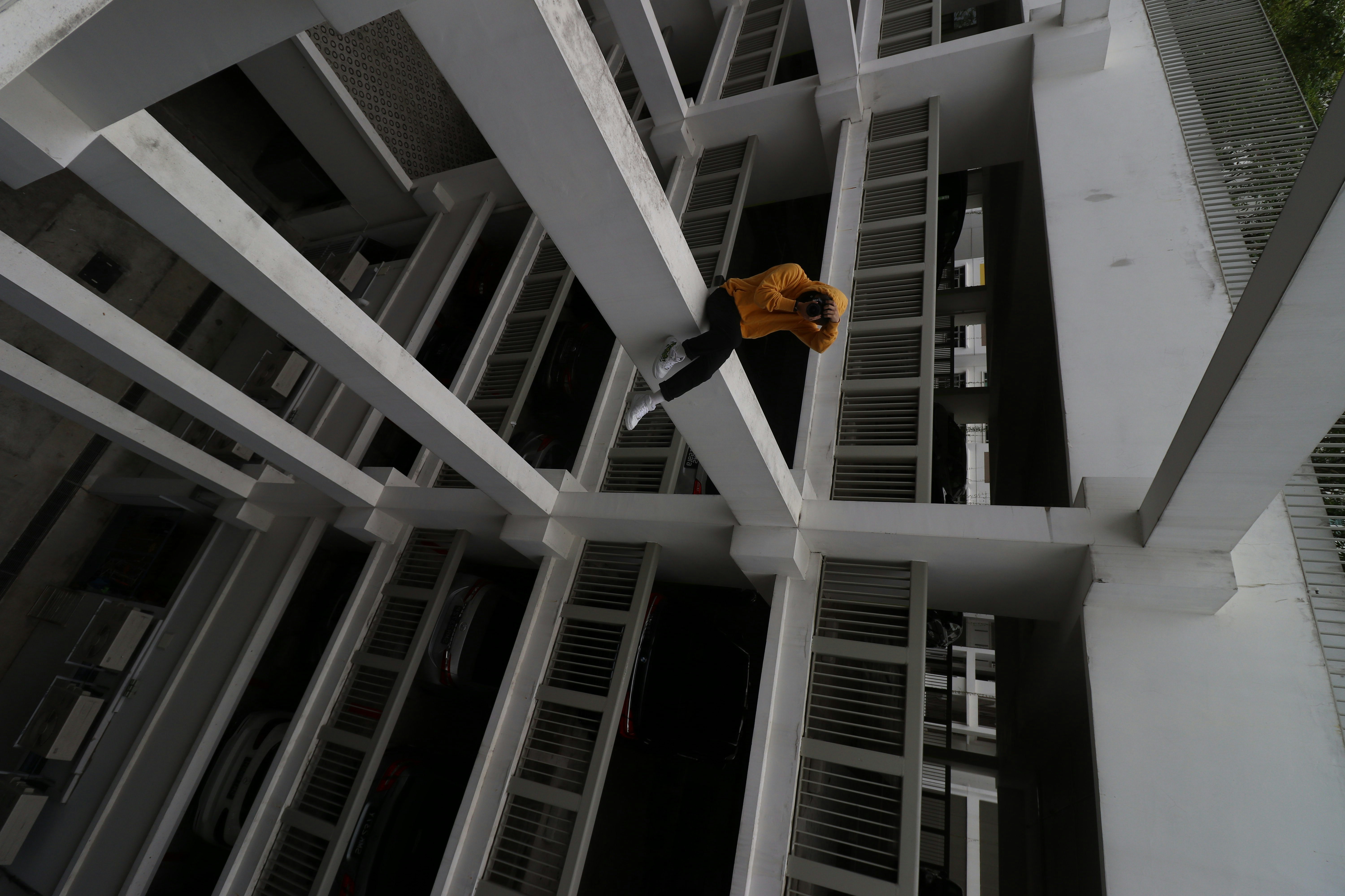 woman in yellow long sleeve shirt and black pants standing on white concrete staircase