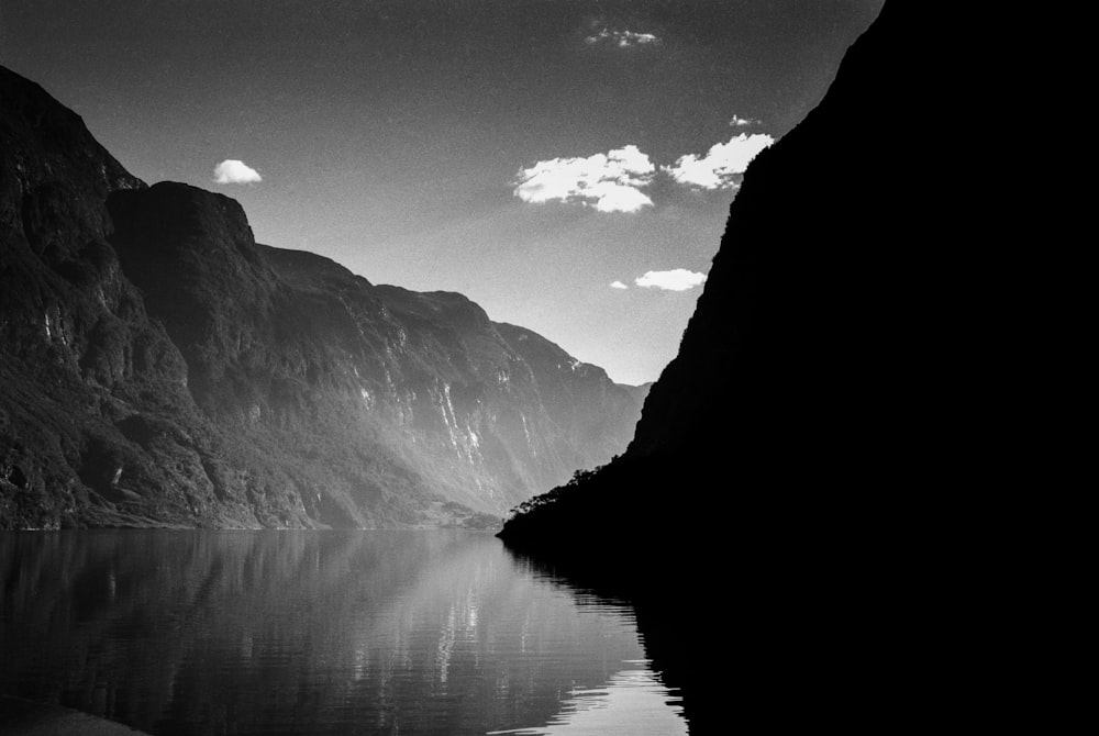 grayscale photo of lake between mountains