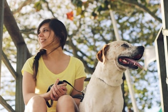 woman in yellow tank top sitting beside white short coated dog