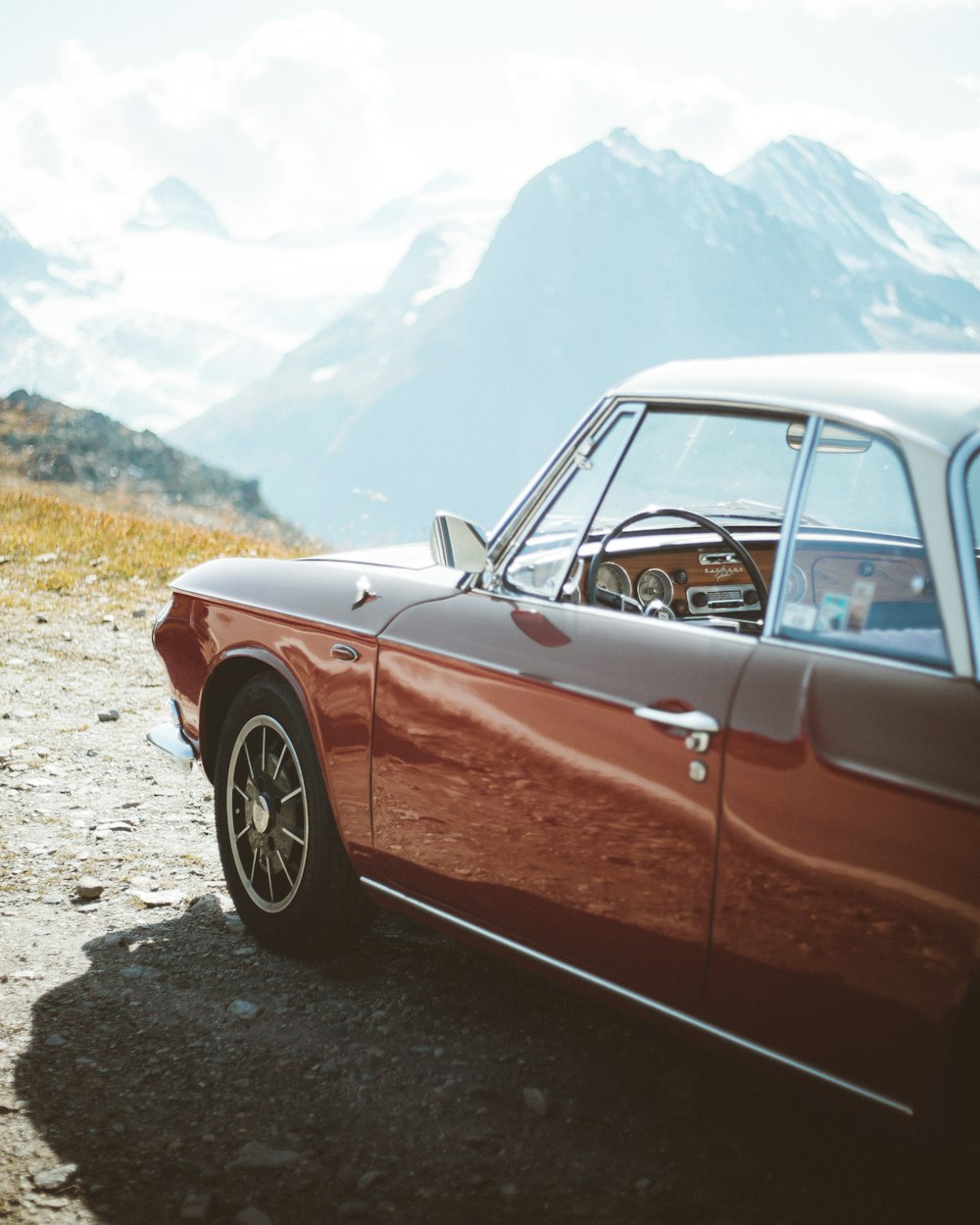 red sedan on gray dirt road during daytime