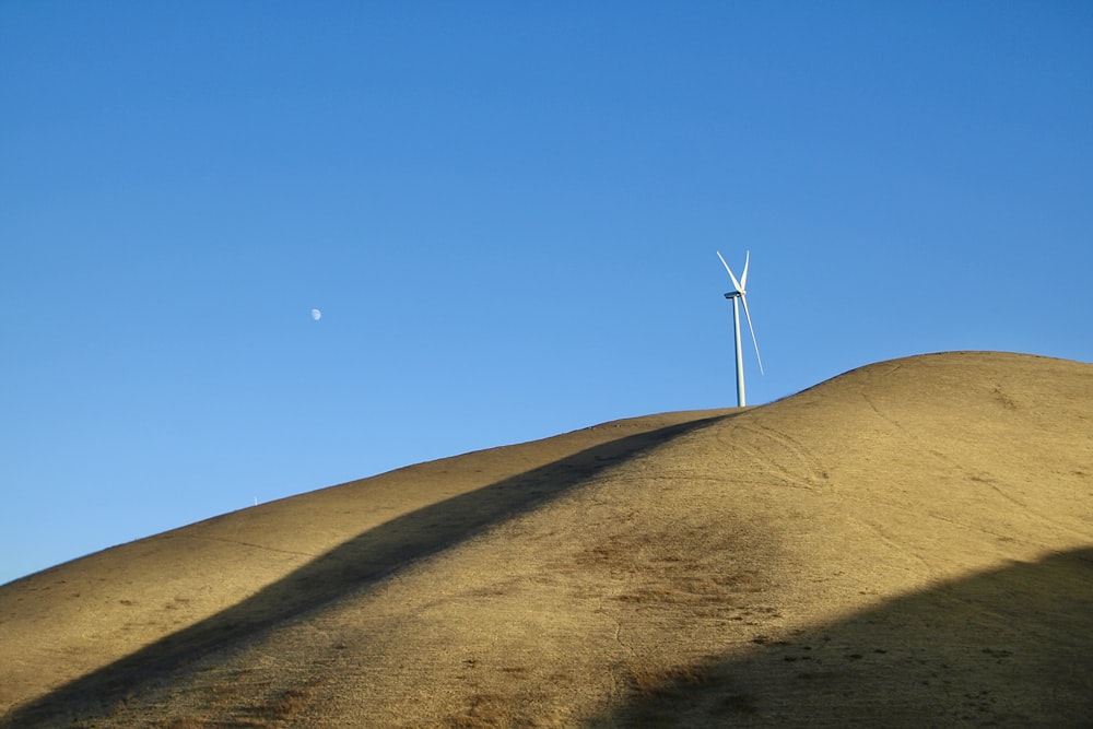 wind turbine on brown sand under blue sky during daytime