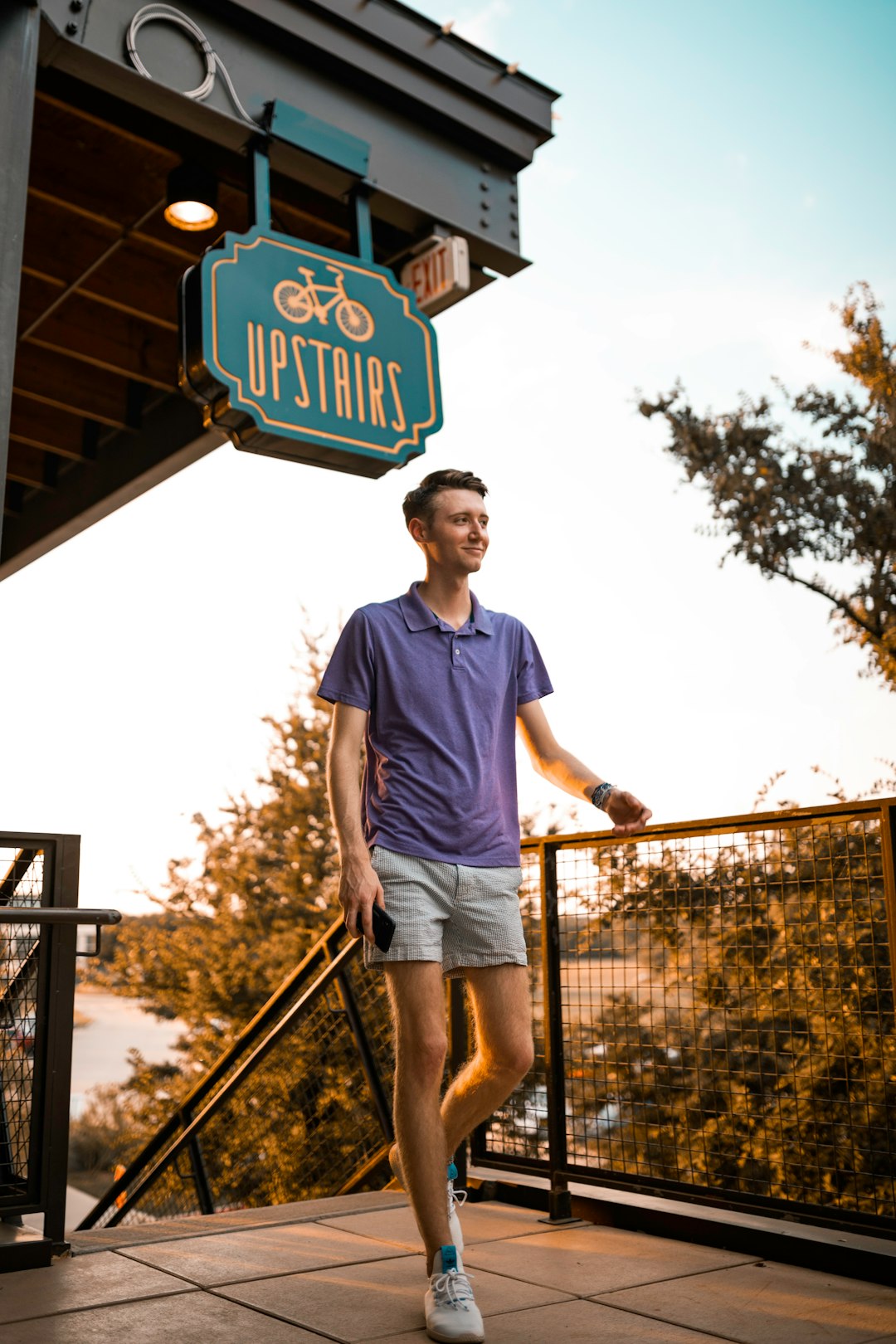 man in blue crew neck t-shirt and brown shorts standing on brown metal railings during
