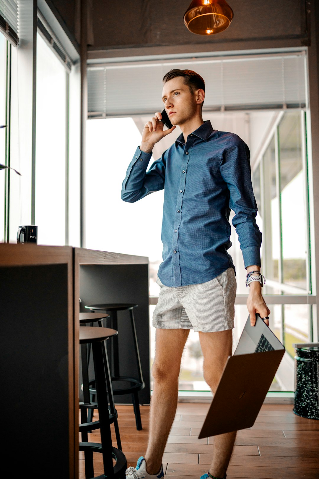 woman in blue denim jacket and blue denim shorts standing beside brown wooden table