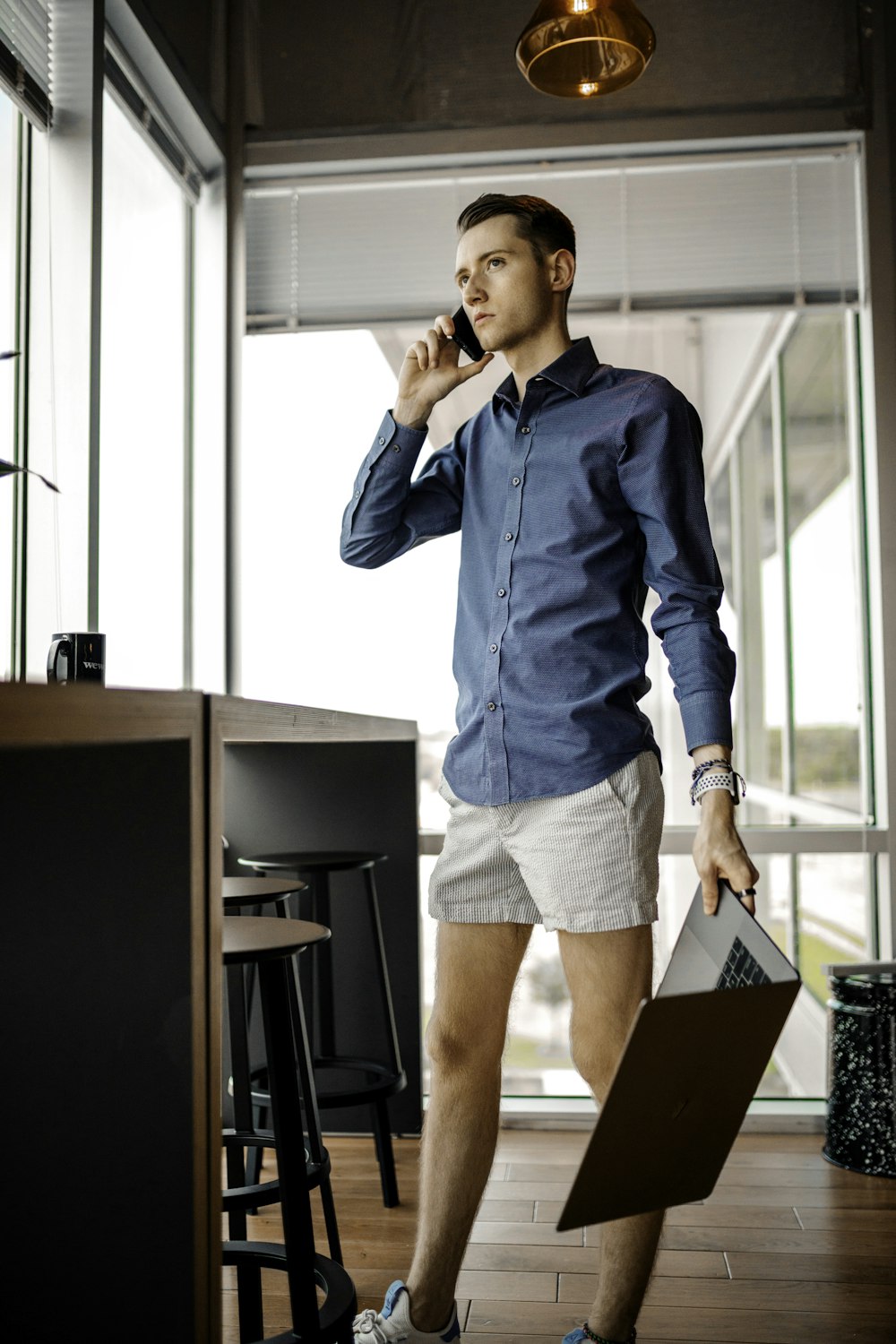 woman in blue denim jacket and blue denim shorts standing beside brown wooden table