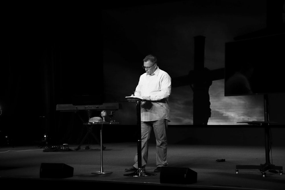 man in white dress shirt standing on stage