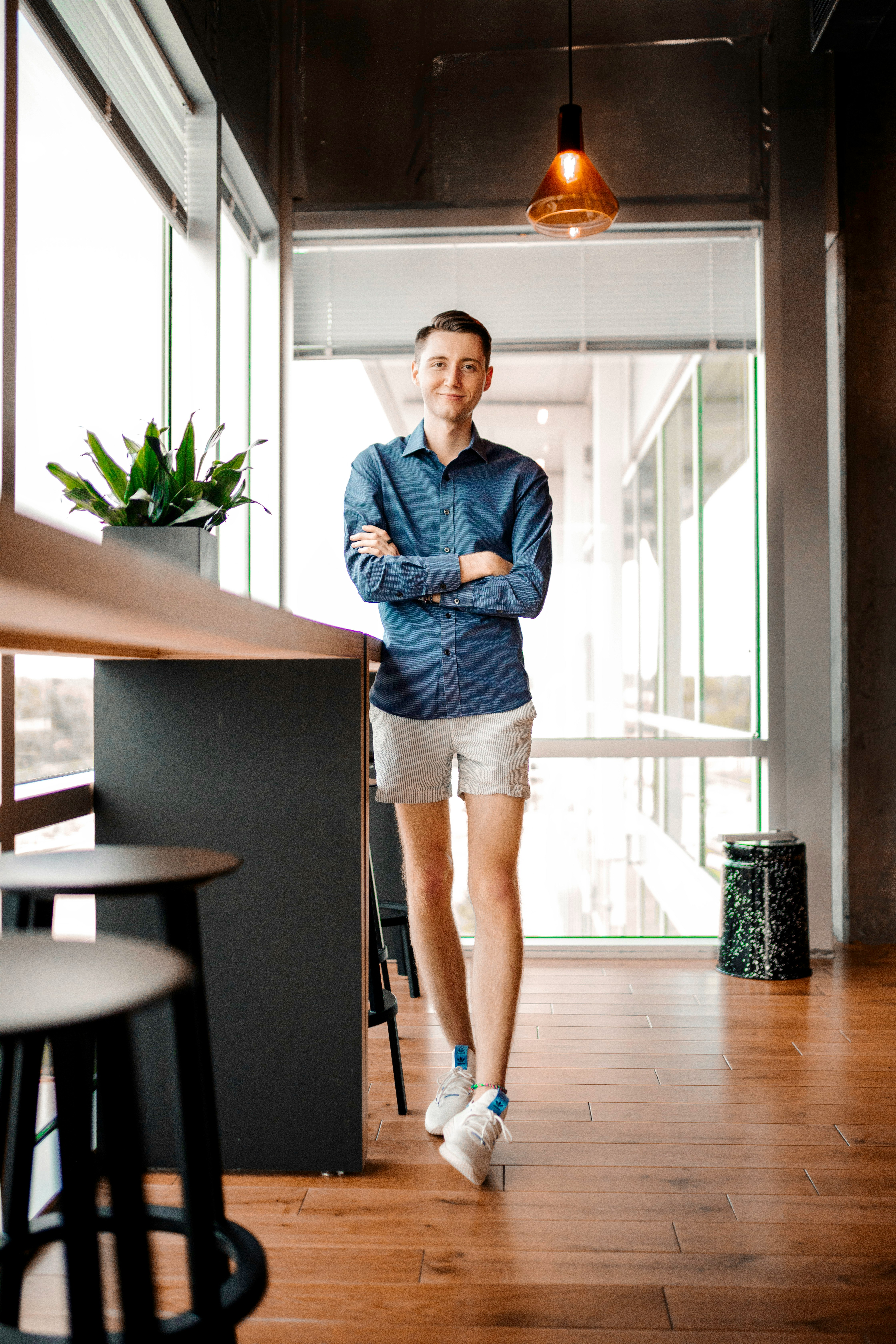 woman in blue denim jacket and white skirt standing beside brown wooden table