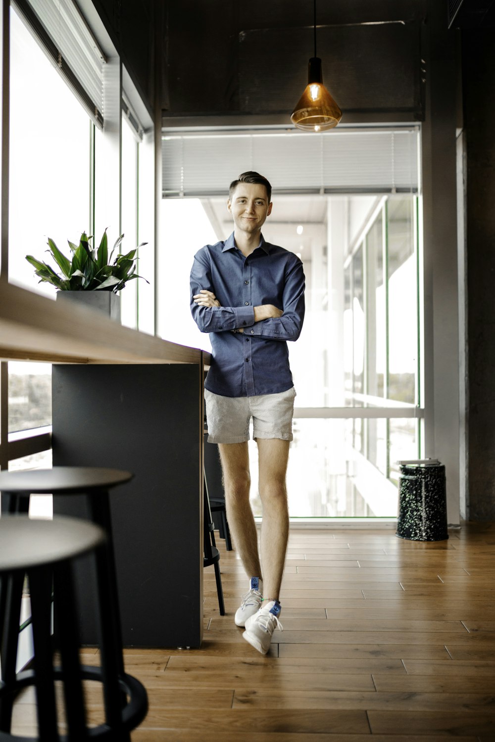 woman in blue denim jacket and white skirt standing beside brown wooden table