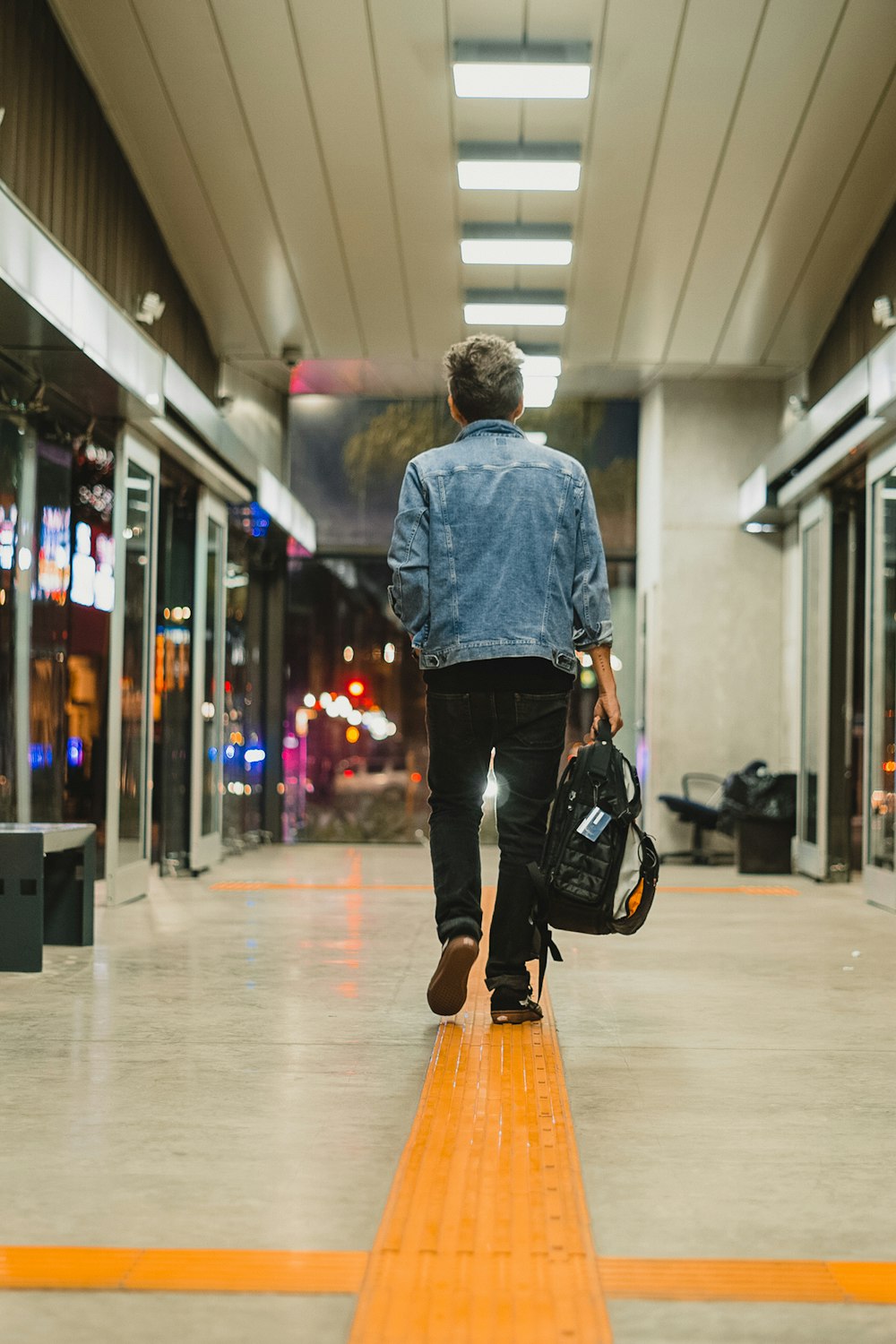 man in blue dress shirt and black pants walking on hallway