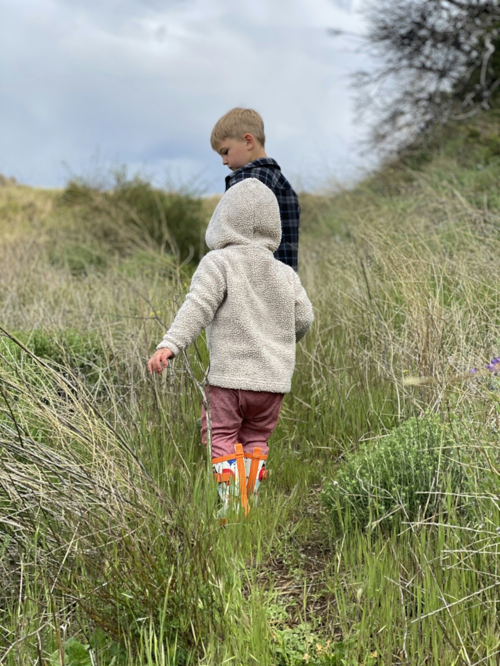 boy in gray hoodie walking on green grass field during daytime