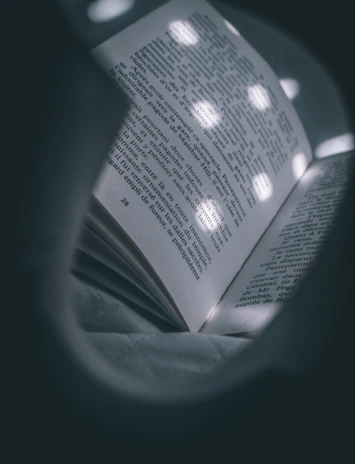 Close-up of an open book with a softly glowing lamp illuminating the pages.