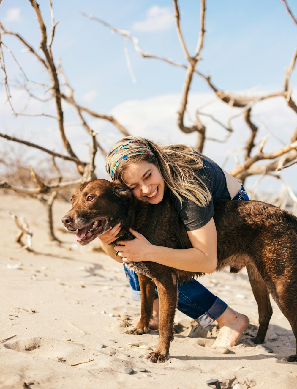 woman in black tank top and blue denim shorts holding brown short coated dog on white