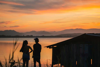 A warm, cinematic portrait of Bruce and Gaynor Richter standing together in a Montana mountain landscape at sunset.