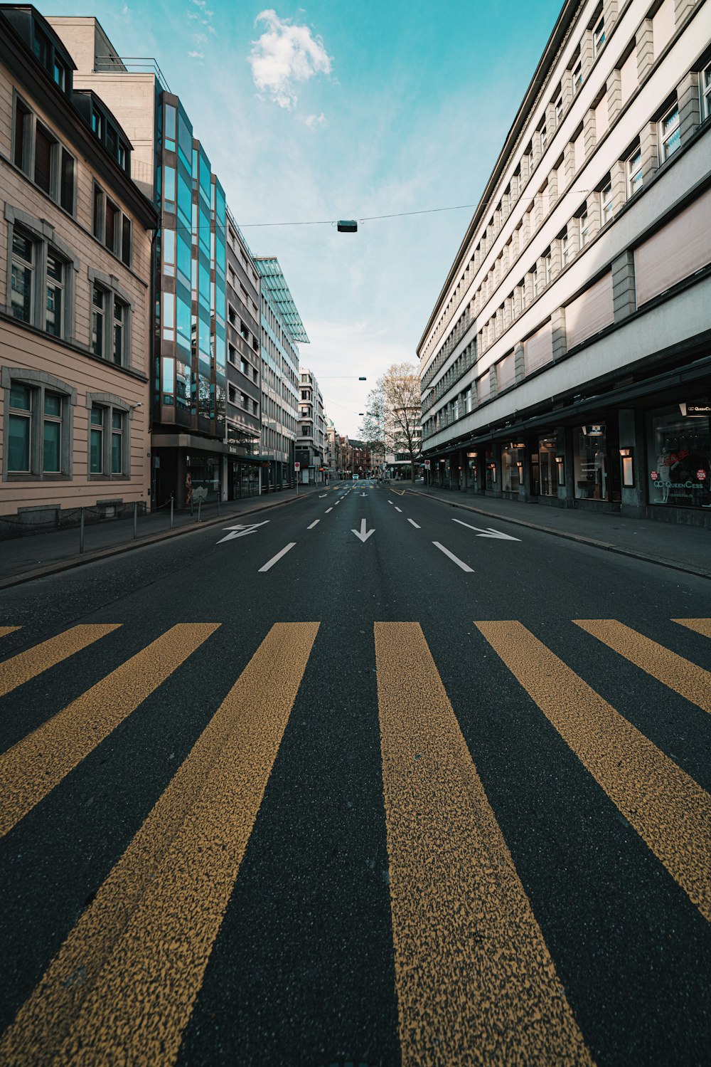 black and yellow pedestrian lane in between of brown and white concrete buildings during daytime