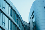 A sleek modern building with large glass windows reflecting the sky, showcasing erdvėja's architectural style.