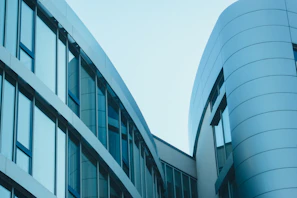 A sleek modern building with large glass windows reflecting the sky, showcasing erdvėja's architectural style.