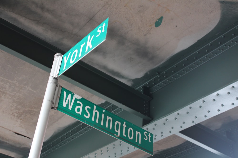 two green street signs on a metal pole