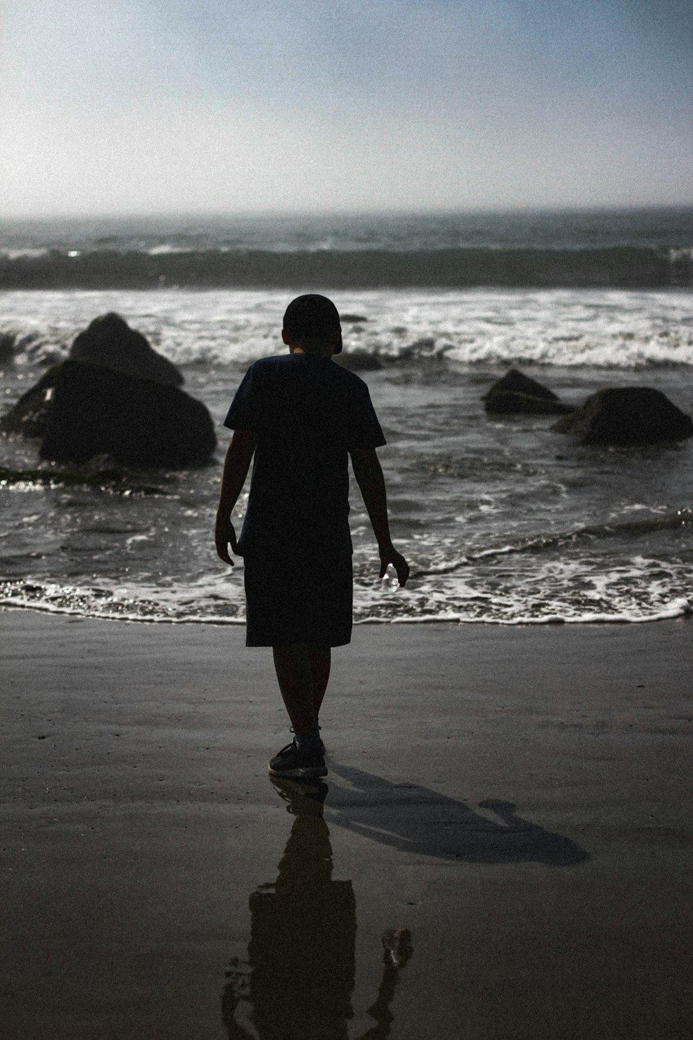 man in black jacket walking on beach during daytime