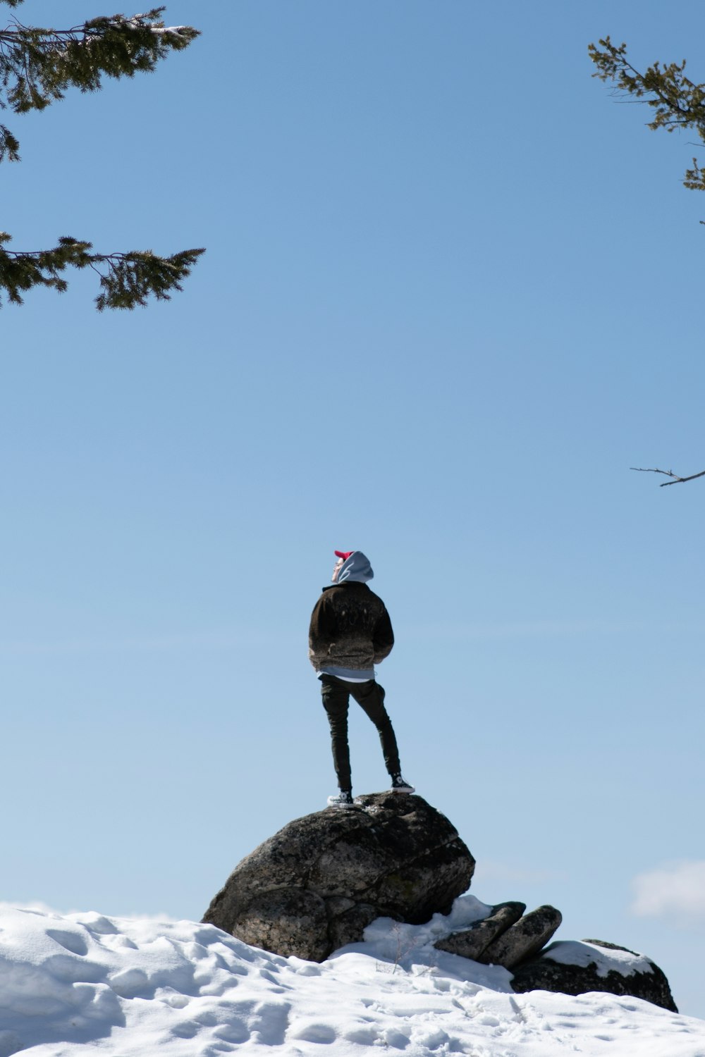 person in black shirt standing on rock near body of water during daytime