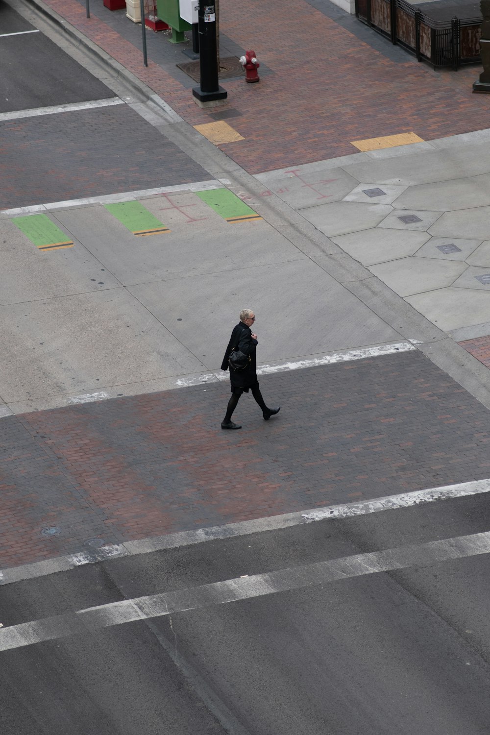 man in black jacket walking on gray concrete pavement during daytime