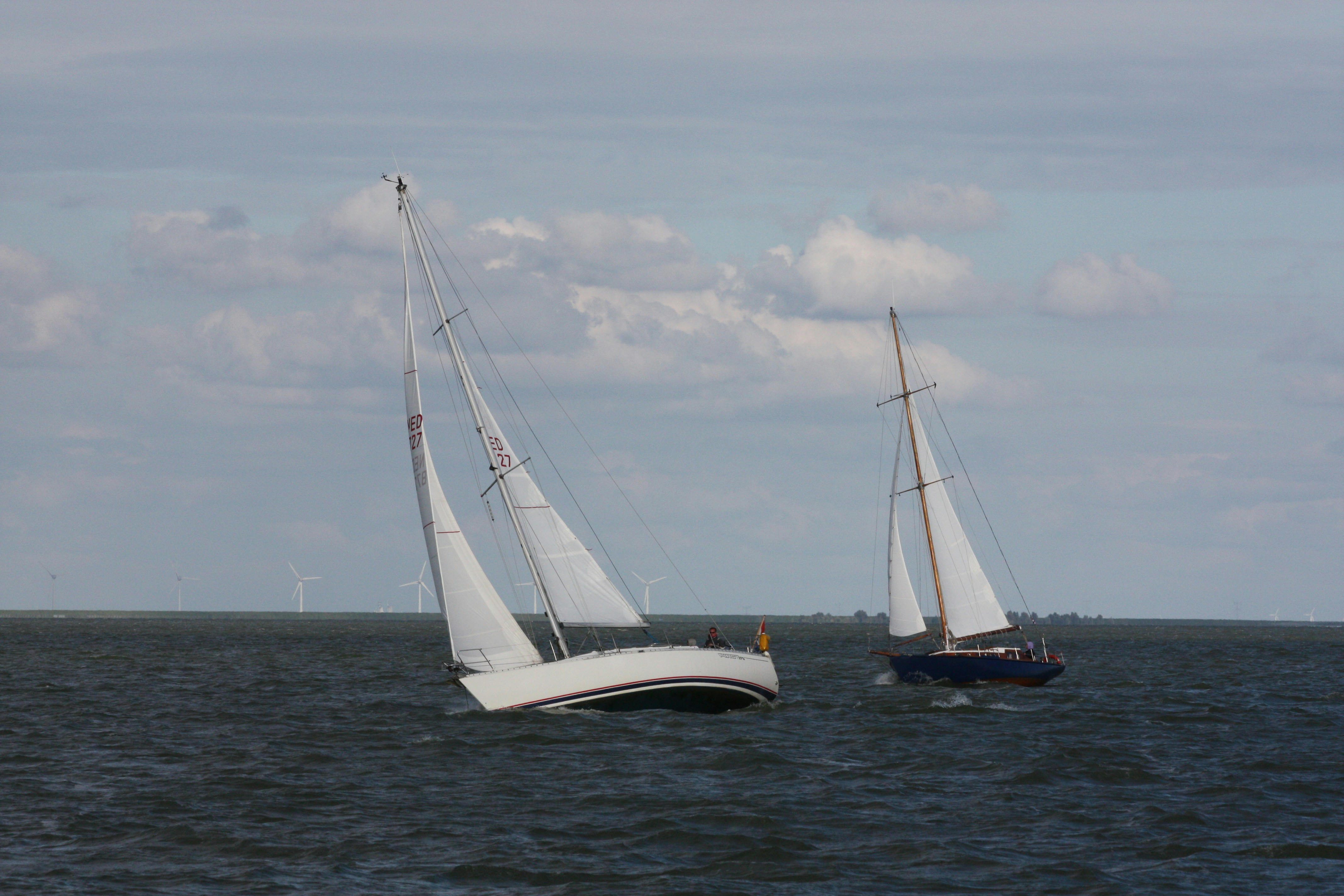 white sail boat on sea under white clouds during daytime
