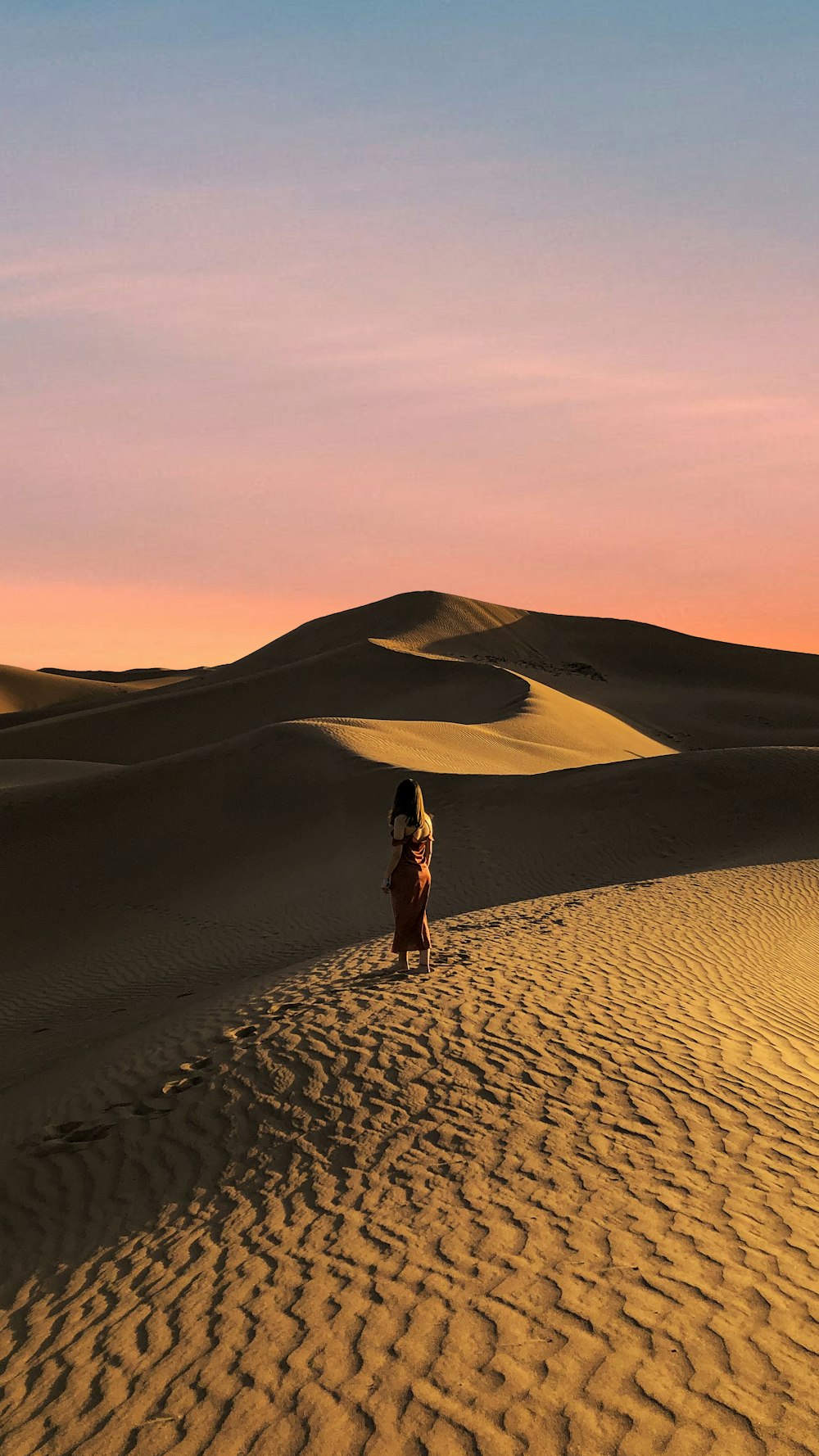 mulher no vestido preto que anda no deserto durante o dia