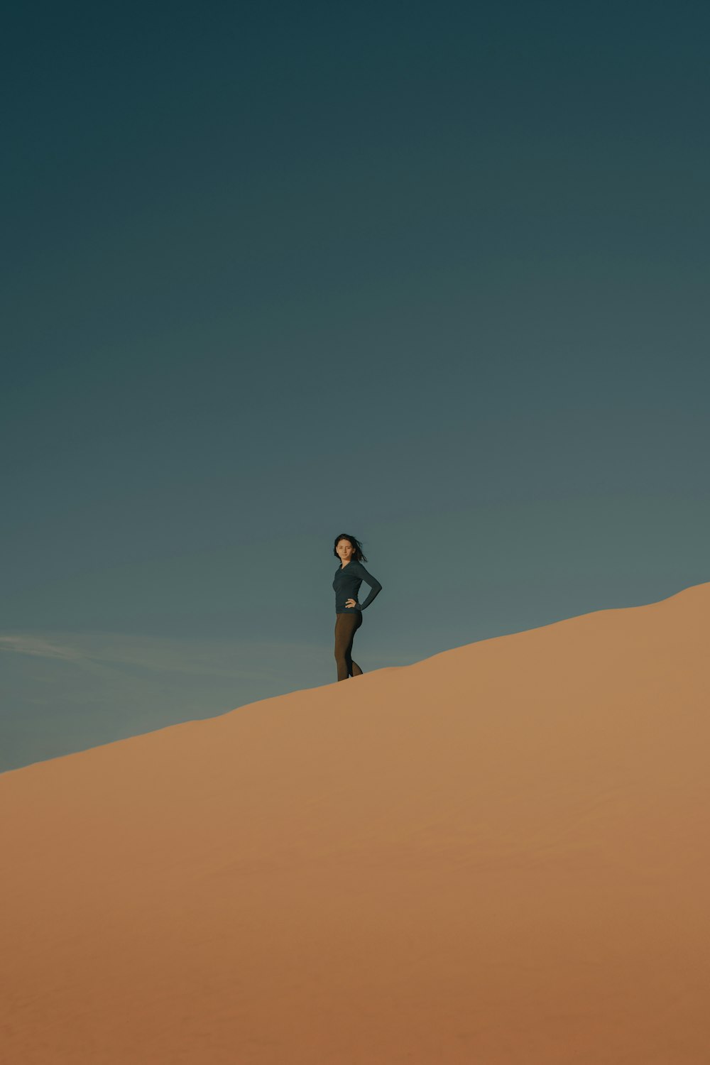 昼間、茶色の砂の上に立っている黒いシャツと黒い短パンの女性