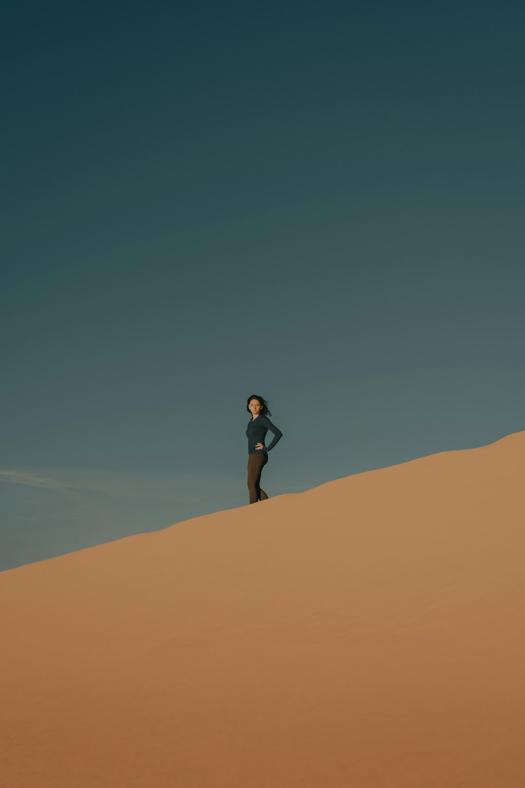 woman in black shirt and black shorts standing on brown sand during daytime