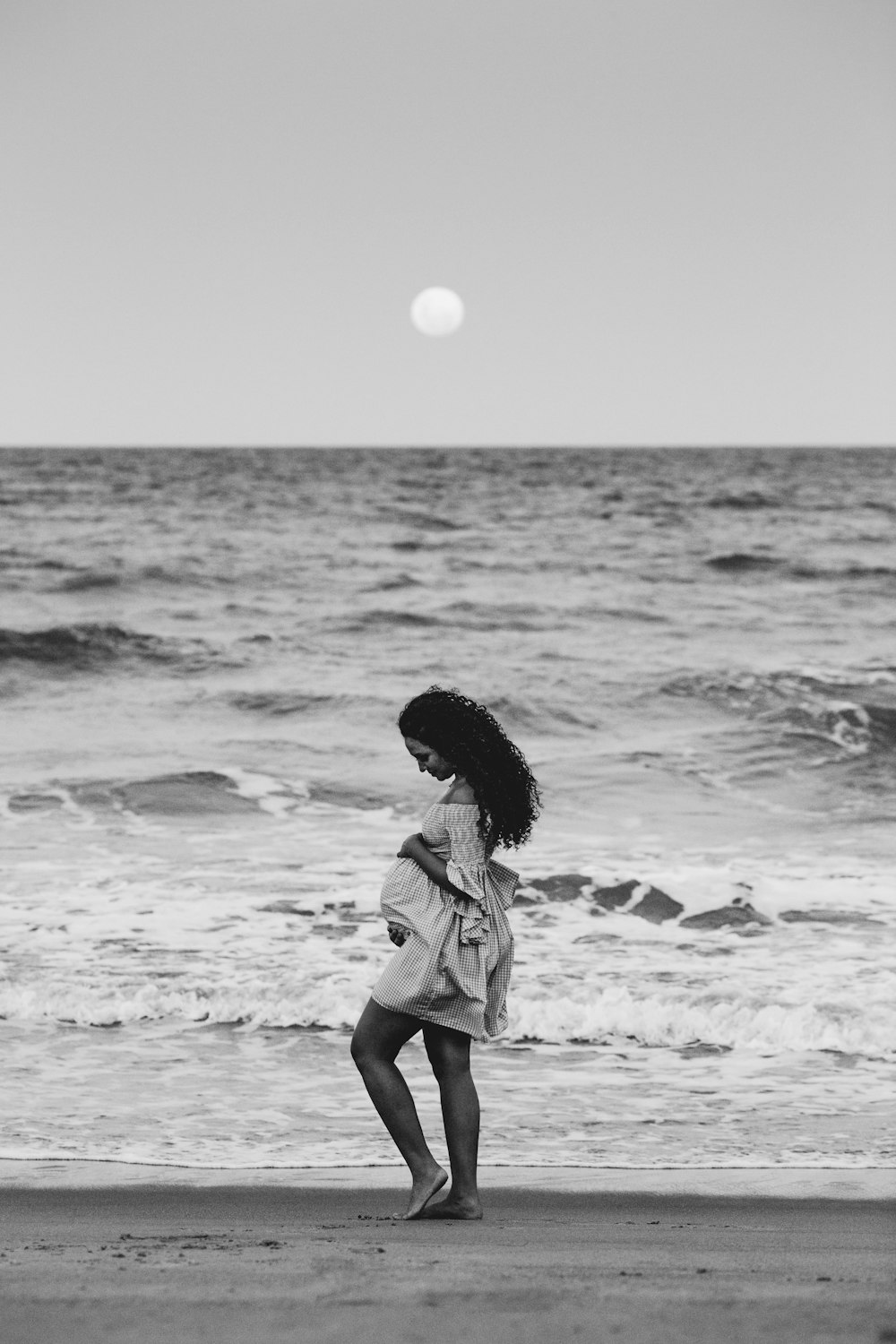 menina no vestido branco e preto em pé na costa durante o dia