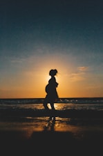 silhouette of woman standing on beach during sunset