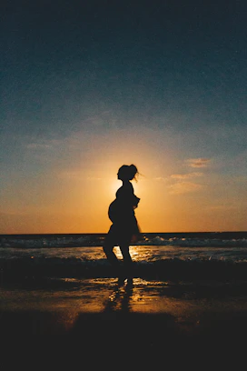 silhouette of woman standing on beach during sunset