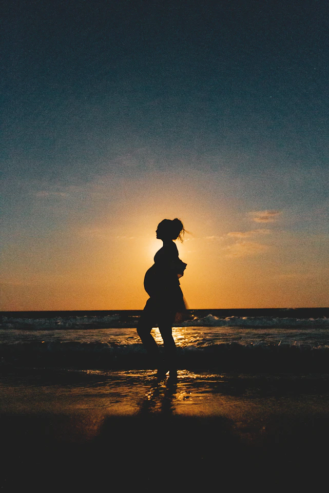 silhouette of woman standing on beach during sunset