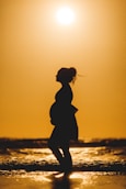 silhouette of woman standing on beach during sunset